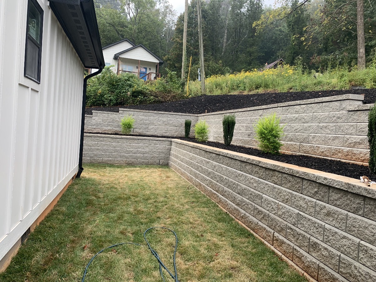 Clean multi-tiered block retaining wall with fresh landscaping